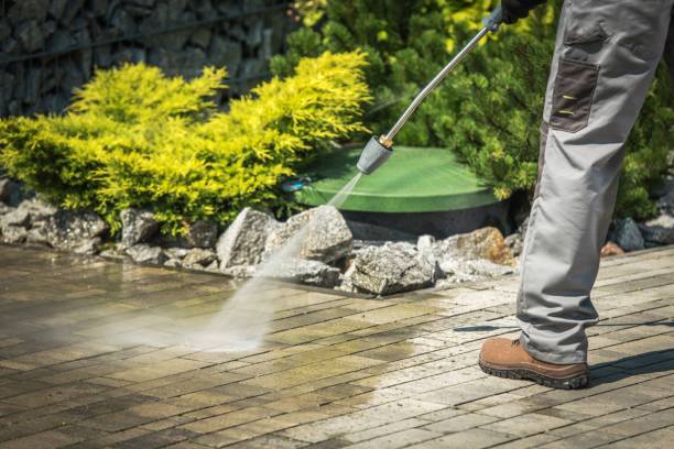 A man pressure washing a brick driveway js pristine clean