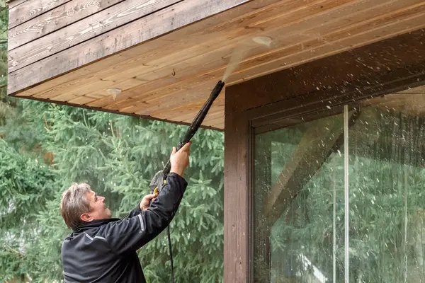 A man cleanig terrace wood planks with pressure washing