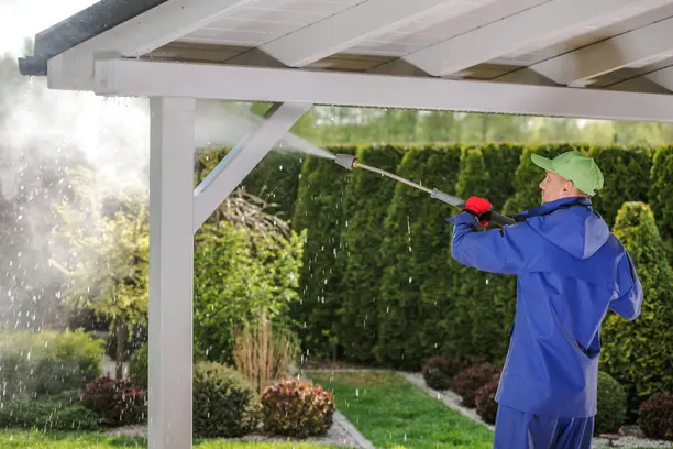 A man pressure washing garden porch wooden roof in los angeles