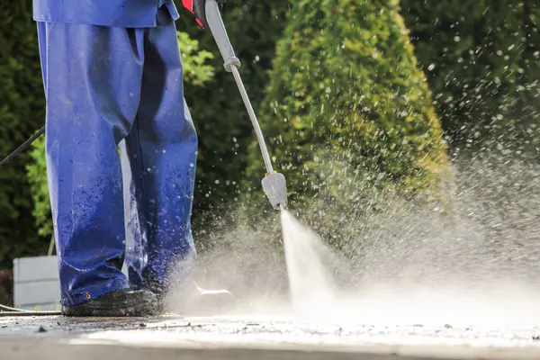 A man pressure washing house driveway