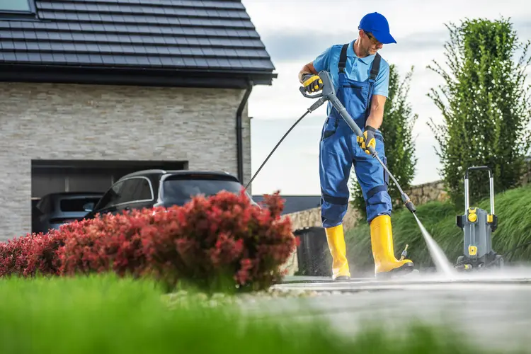 A man pressure washing to clean driveway