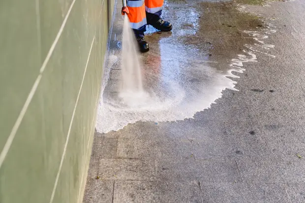 Cleaning worker pressure washing to clean the sidewalks of a city in pasadena