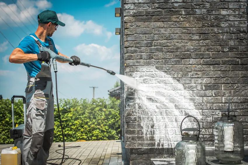 A man pressure washing brick walls to clean dirt