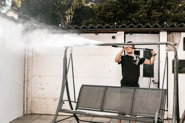 A man pressure washing garden swing