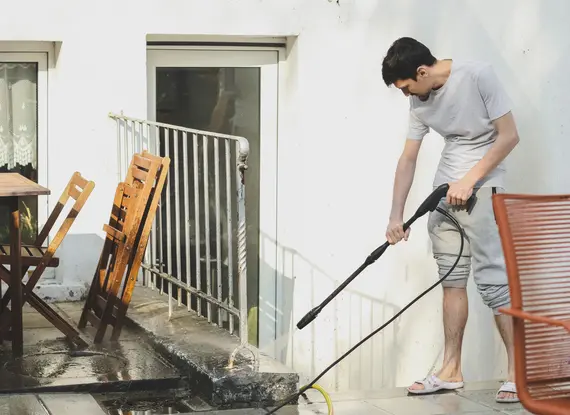 A man washing fence using pressure washing