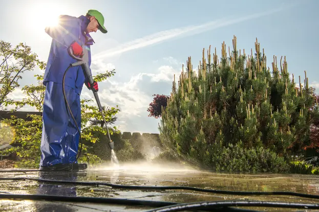 A worker cleaning garden bricks using pressure washing