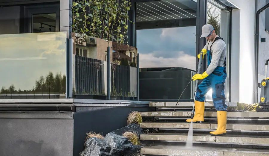 A worker pressure washing garden paths