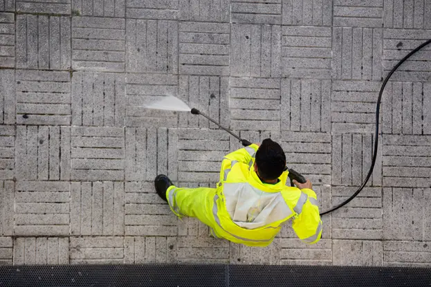 A worker pressure waashing street sidewalk