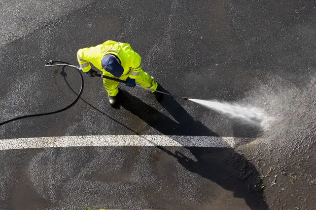 A worker pressure washing streets sidewalk