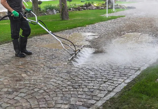 Worker pressure washing muddy concrete bricks in santa ana