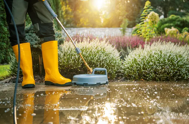 a man cleaning patio in a garden by pressure washing