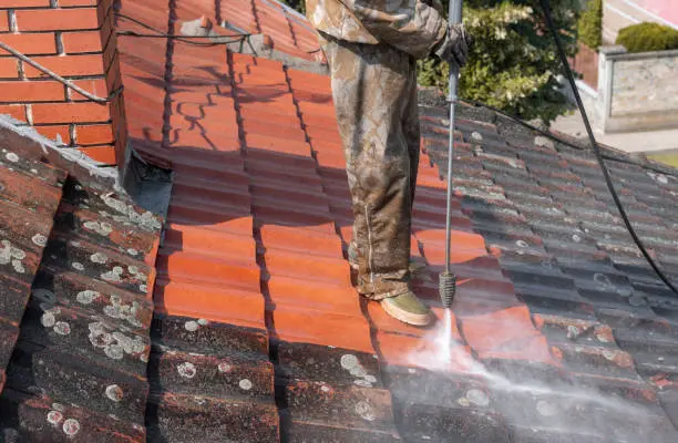 A worker cleaning roof with high pressure