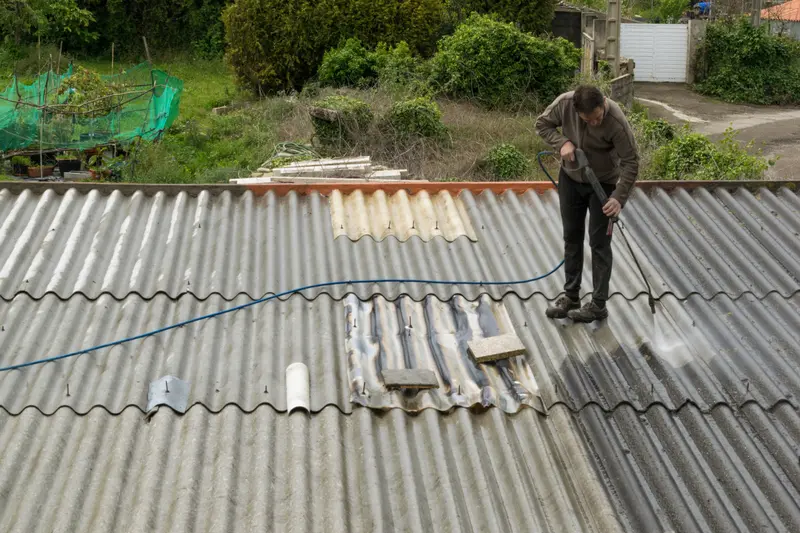 Worker Cleaning roof stain with pressure washing gun