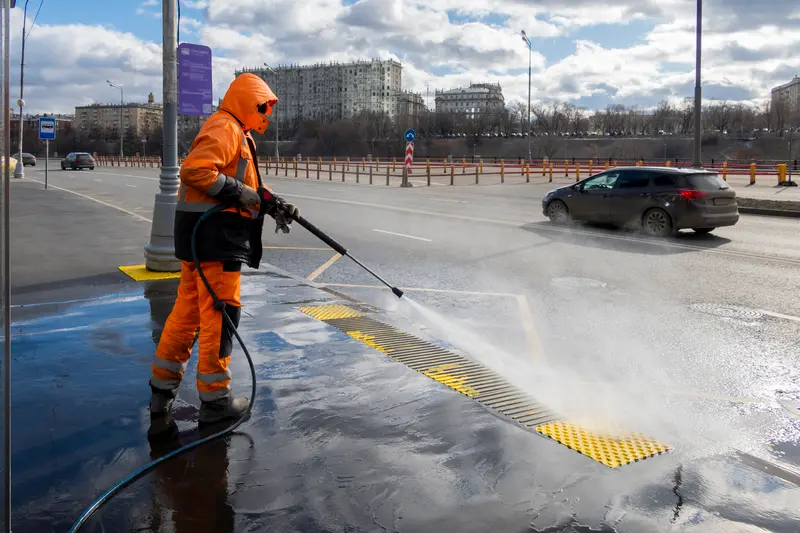 Worker cleaning city walkways with pressure washing